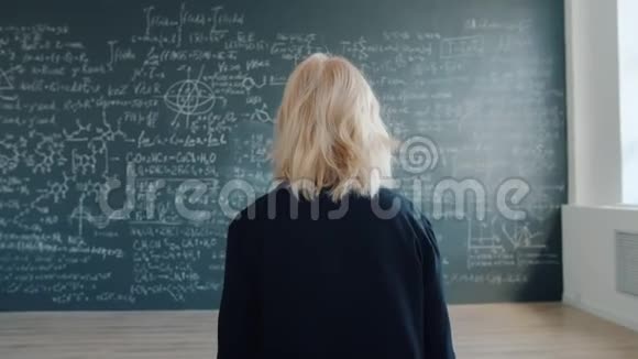 女教授在课堂上缓慢地走向黑板看公式视频的预览图