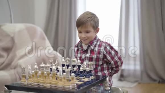 聪明的白人男孩把棋子放在船上的肖像小可爱的孩子开始玩不可辨认的游戏视频的预览图