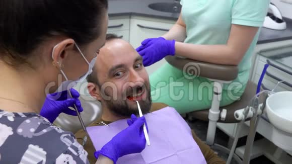 男性患者正在咀嚼特殊的牙科指示器牙医正在检查它视频的预览图