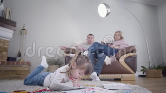 一幅可爱的黑发白种人女孩的肖像她的父母坐在沙发上背景是书视频的预览图