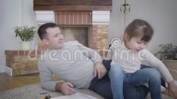 镜头跟随漂亮的白人女孩从父亲身边走过躺在壁炉前柔软的地毯上走向母亲视频的预览图