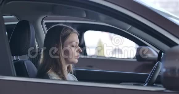 年轻自信的高加索女人坐在汽车里摸着方向盘女士选择汽车视频的预览图