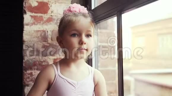 漂亮可爱的女婴金发女孩头上戴着粉红色的蝴蝶结沿着窗户走慢动作在斯塔迪加姆射击视频的预览图