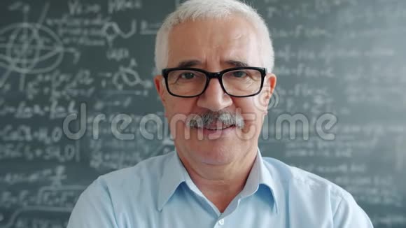 幸福的成熟男人戴着眼镜看着黑板旁的镜头微笑的画像视频的预览图