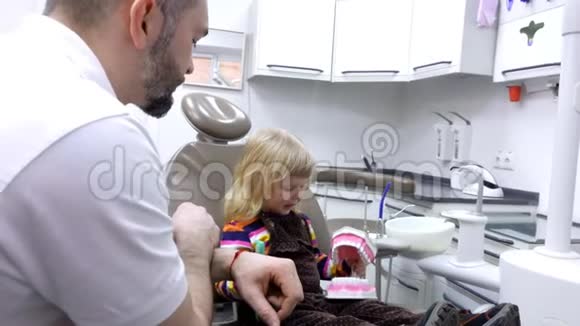 小女孩学着用牙刷在下巴模型上清洁牙齿视频的预览图