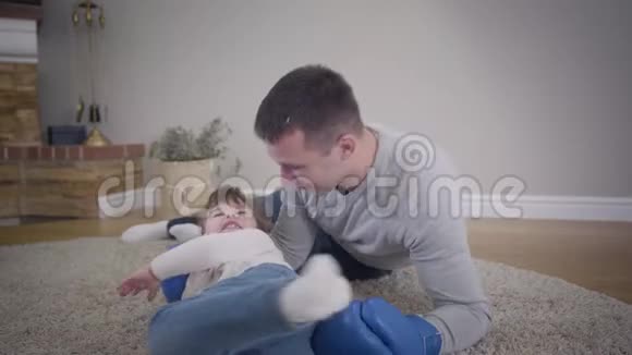 快乐的白人男人和小女孩在家里地板上玩耍布鲁内特的女儿站起来把父亲留在家里视频的预览图