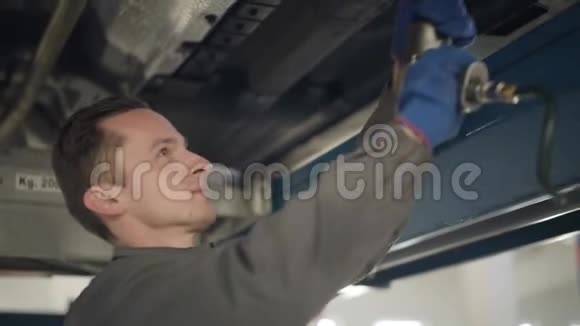 近距离侧面观察自信的白人男子在工作服使用专业设备的汽车维修年轻男性视频的预览图