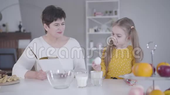 勤劳的小女孩帮奶奶烤薄饼的肖像很漂亮的白人孩子视频的预览图