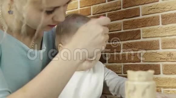 快乐的母亲用勺子喂粥给家里的小女儿小女孩有水痘视频的预览图