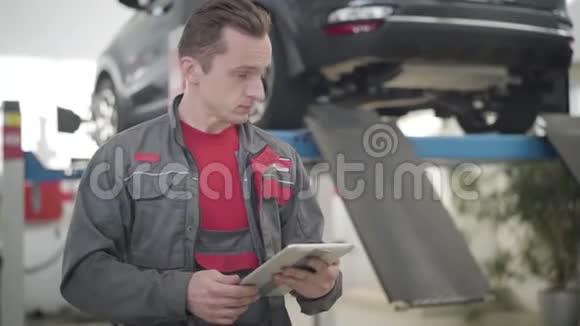 集中白人男子使用平板电脑和回顾汽车在修理店的肖像专业汽车视频的预览图