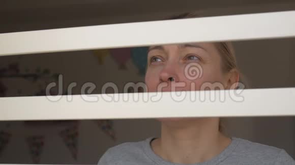 一个戴着医用口罩的女人从窗外透过铁栏看着视频的预览图