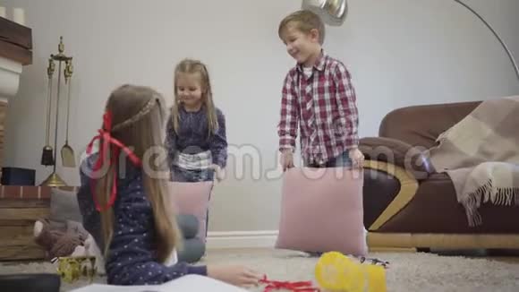 小白种人男孩和女孩用枕头和姐姐打架十几岁的女孩站起来加入游戏视频的预览图