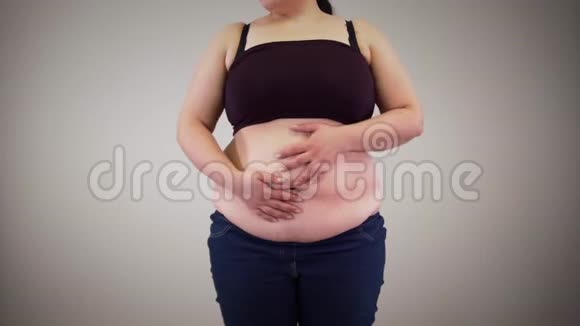 无法辨认的白人女人在肚子上摇晃脂肪肥胖的年轻女人摸着肚子超重肥胖不健康视频的预览图