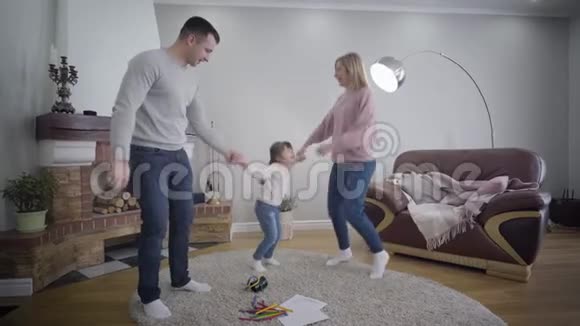 快乐的白种人家庭在室内玩母亲和父亲牵着女儿手跳舞和抚养视频的预览图
