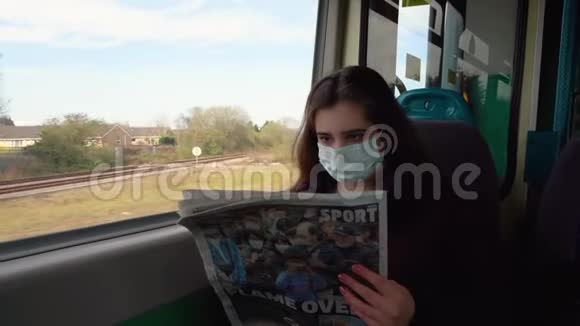 一位年轻女士戴着医疗面具坐火车旅行看报纸视频的预览图