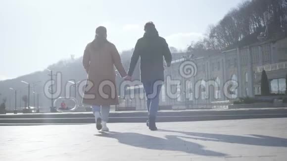 镜头跟随年轻男女在阳光明媚的秋日漫步在城市广场快乐的高加索夫妇相爱视频的预览图