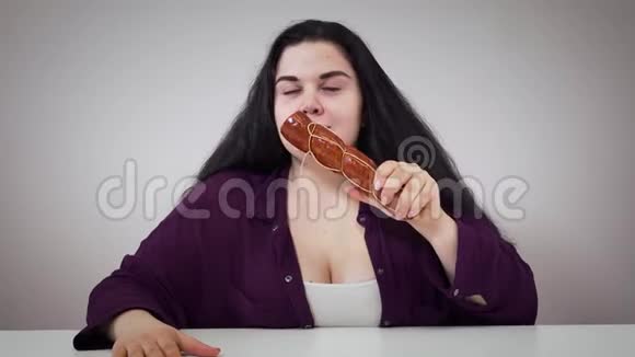 丰满的白种女人闻着香肠贪婪地吃着胖黑发女孩饥肠辘辘地咬着食物肥胖视频的预览图