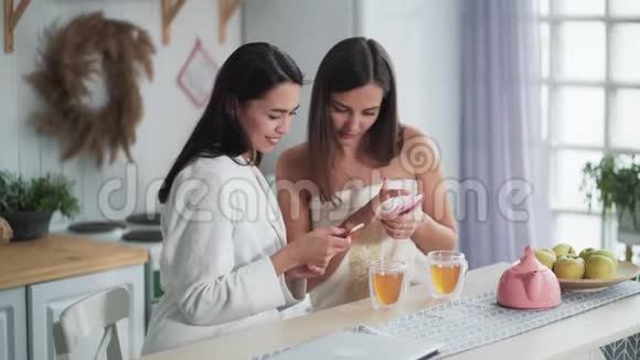 两个女人吃早餐喝茶看电话和微笑网购视频的预览图