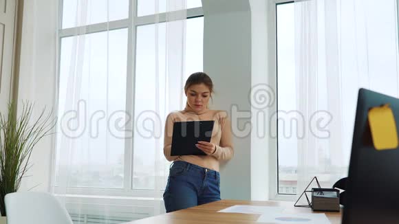 站在窗边写字的年轻女商人视频的预览图