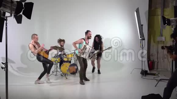 拍了一个朋克摇滚乐队的片段一个摄影师在工作音乐家们正在用乐器跳跃低音视频的预览图