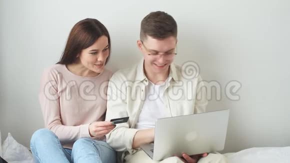 年轻人和他漂亮的妻子用信用卡在网上购物视频的预览图