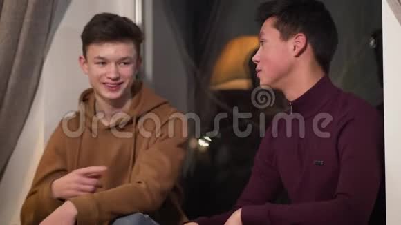 白人和亚洲朋友谈论和给予达普的肖像青少年朋友晚上在室内度过快乐的人视频的预览图