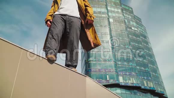 酷的现代时尚男人背景下美丽的高层建筑作为超级英雄他穿着一件棕色的外套视频的预览图