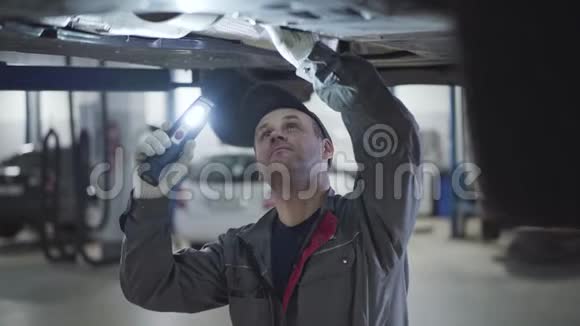 成人白种人维修工程师用手电筒在车底照明和手动检查车底的画像视频的预览图