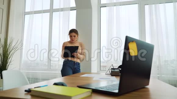 年轻的女商人站在办公室的窗户边写字视频的预览图
