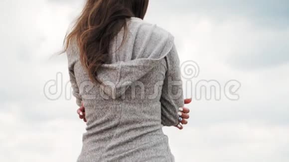 穿着灰色兜帽毛衣的孤独女孩沿着海岸的大海走慢动作特写视频的预览图