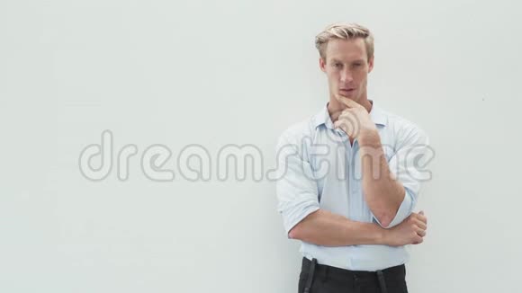有思想的金发男子的肖像穿着衬衫双手交叉在白色背景上视频的预览图