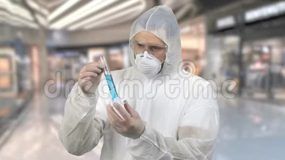 男子穿抗病毒防护服持试管用蓝色药物视频的预览图