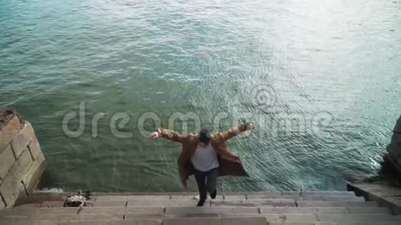 快乐的年轻人上楼梯时积极跳舞场景拍摄于河底的城市公园视频的预览图