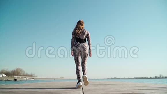 一位身材优美的女运动员在湖边的码头上奔跑慢动作视频的预览图