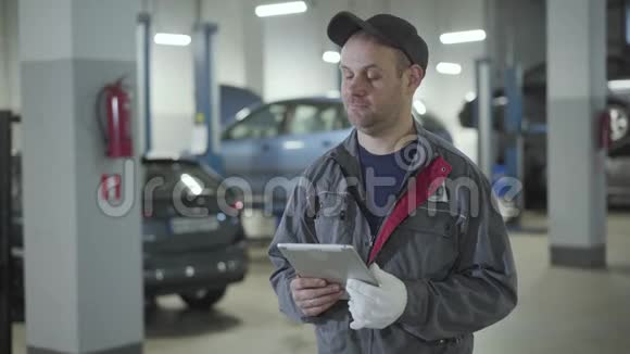 成人职业白种人汽车机械师在修理店里四处寻找自信的人拿着平板电脑站在视频的预览图