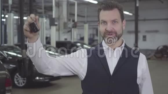 一幅自信成功的白种人的肖像他右手拿着车钥匙看着相机汽车车主视频的预览图