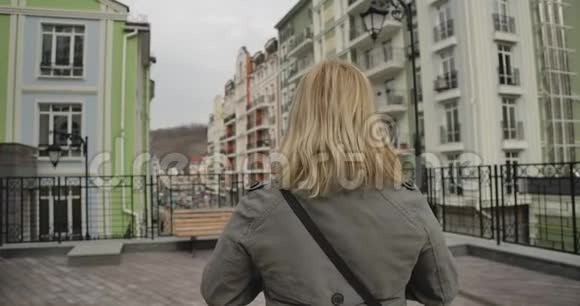 后景特写一位身穿秋装的金发女子站在城市街道上高加索族退休人员四处旅行视频的预览图