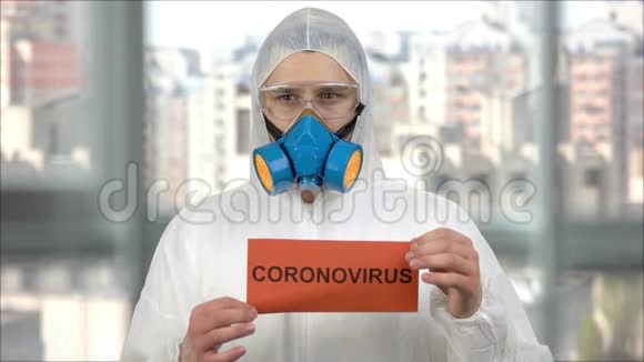 穿着防护服和带冠状病毒字样的呼吸面罩持纸的人视频的预览图