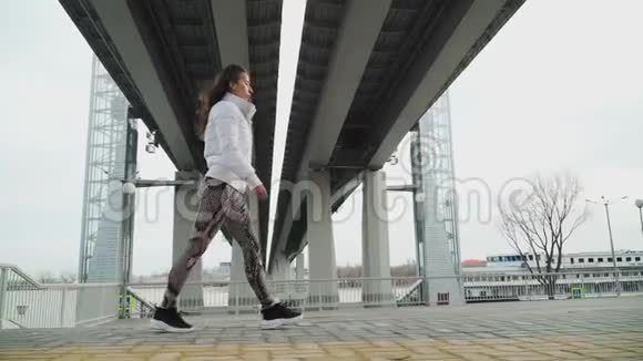 穿着白色夹克的严肃女孩正沿着这条路快速地走下高桥对斯泰迪达姆的射击视频的预览图