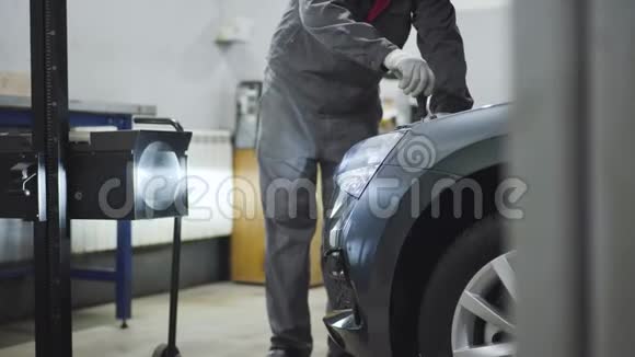 无法识别的男性汽车机械师拧紧螺丝在打开的汽车引擎盖与螺丝刀男性专业人员视频的预览图