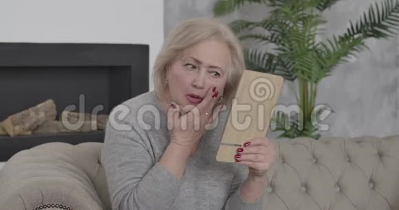 棕色眼睛的高白种人女人收起手镜和挥动手的肖像愤怒的富有退休者视频的预览图