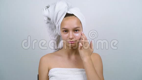 裹着白色毛巾的可爱女孩洗澡后涂上面霜视频的预览图