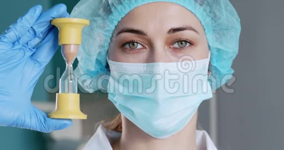 戴防护面罩的女医生手拿沙漏视频的预览图
