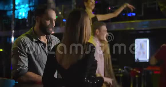 年轻的中东英俊的男人在夜总会和一个面目全非的白人女人说话快乐的多种族夫妇视频的预览图