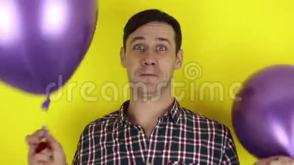 一个有趣可爱的家伙积极玩紫色气球并吹在聚会的号角视频的预览图