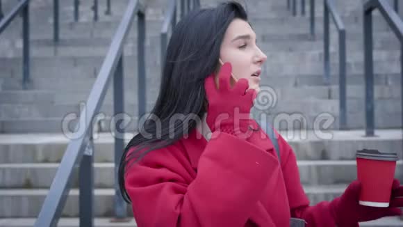 一位焦虑的高加索女人站在户外拿着咖啡杯在电话里交谈年轻优雅视频的预览图