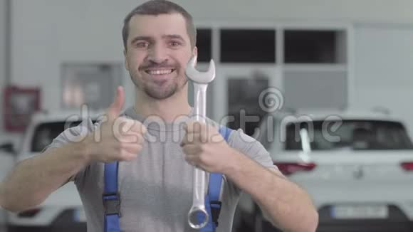 一幅开朗的白种人的肖像棕色的眼睛拇指举起扳手快乐男汽车机械师视频的预览图