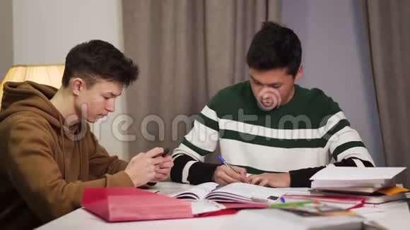 一幅专注的亚洲男孩做功课的肖像作为他的高加索同伴惹恼了他少年表现出某种视频的预览图