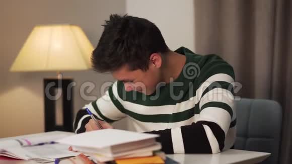 近距离观看微笑的亚洲男孩写在工作簿和看书快乐的青少年学生视频的预览图