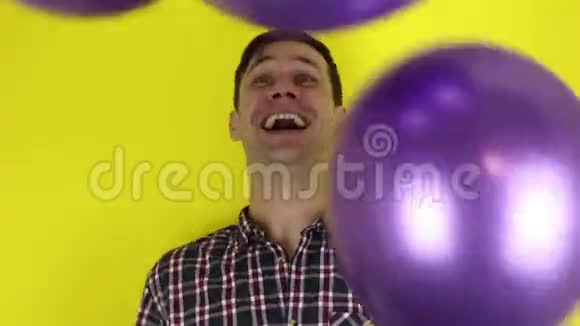 一个有趣可爱的家伙正在积极地玩紫色气球一个漂亮的家伙在玩气球庆祝他的生日一个门廊视频的预览图